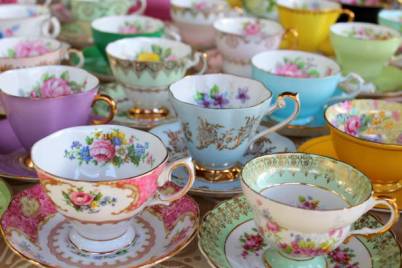 Vintage pastel and floral china tea cups lined up in rows and in stacks.